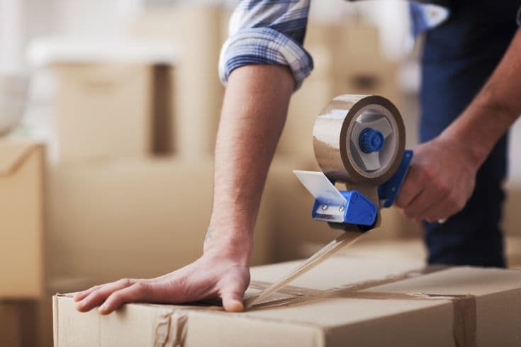 Persona sellando una caja de mudanza con cinta