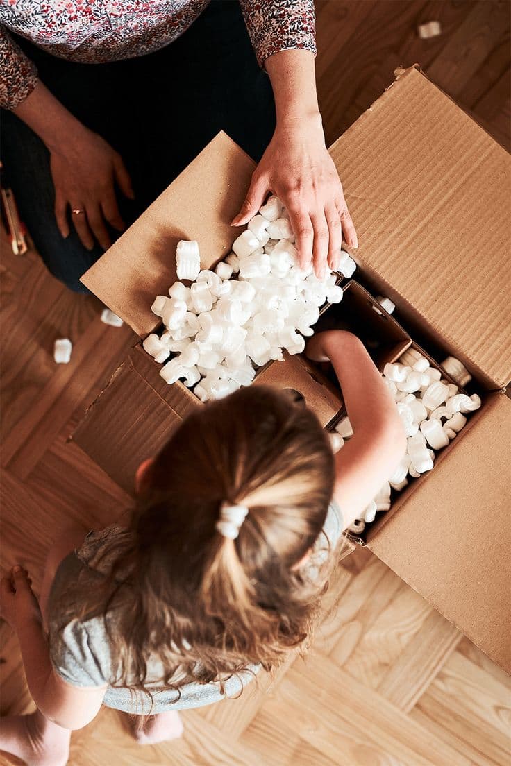 Niña ayudando a desempacar una caja con material de protección