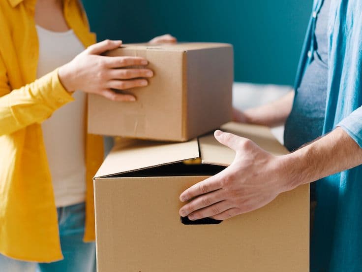 Dos personas pasándose una caja de mudanza